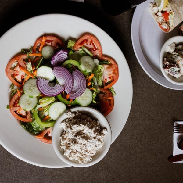 A fresh garden salad with tomatoes, cucumbers, and red onions, served with a side of tuna salad.